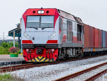 Freight train hauling shipping containers along a rail line