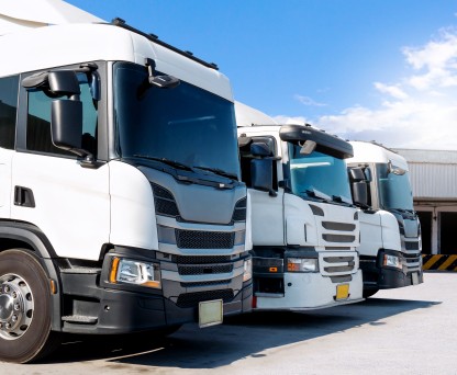 Row of white semi trucks parked at a loading dock