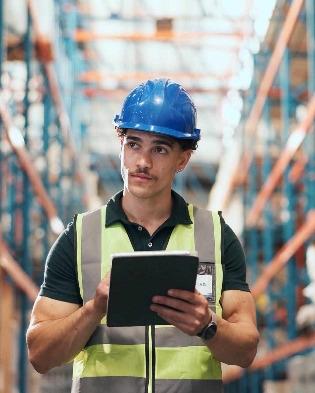 Warehouse worker in a hard hat checking inventory on a tablet